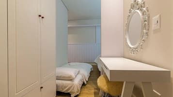 Quarto com cama, guarda-roupa, penteadeira com espelho e um banquinho macio.