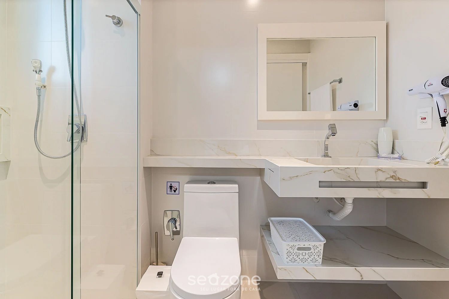 A modern bathroom with a glass-enclosed shower, a toilet, and a sink with a mirror above it.