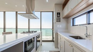 Una cocina moderna con una isla grande, horno empotrado y vistas al mar.