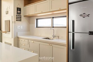 A modern kitchen with a stainless steel refrigerator, a window above the sink, and a wooden countertop. - Apto moderno c/ vista mar a 75m da praia LLR802 (Porto Belo)