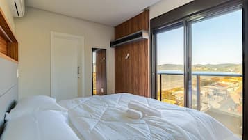 Una habitación de hotel moderna con una cama grande, un panel de pared de madera, una puerta corredera y un balcón con vistas a la ciudad.
