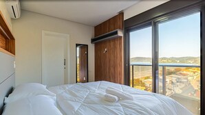 Una habitación de hotel moderna con una cama grande, un panel de pared de madera, una puerta corredera y un balcón con vistas a la ciudad.
