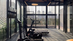 Een moderne sportschool met trainingsapparatuur, grote ramen en uitzicht op gebouwen.