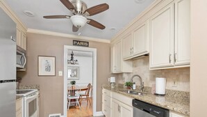 A kitchen with white cabinets, a granite countertop, a ceiling fan, a dishwasher, and a microwave. - Charming Cottage - Near I-75 & Horse Park + Farms (Lexington)