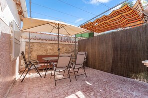 A patio with a table and chairs, a large umbrella, and a wooden fence.