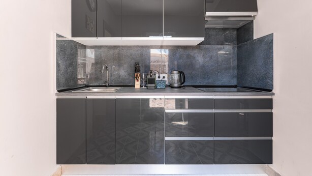 A modern kitchen with dark cabinets, a stainless steel sink, and a built-in range hood.