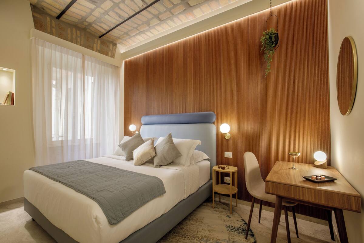 Ein modernes Schlafzimmer mit einem großen Bett, einer Wand mit Holzvertäfelung, einem kleinen Tisch mit Lampe und einem Sessel.