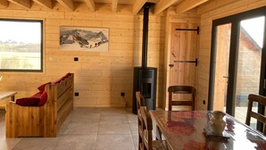 A wooden interior with a fireplace, a bench, a dining table, and a window with a mountain view.
