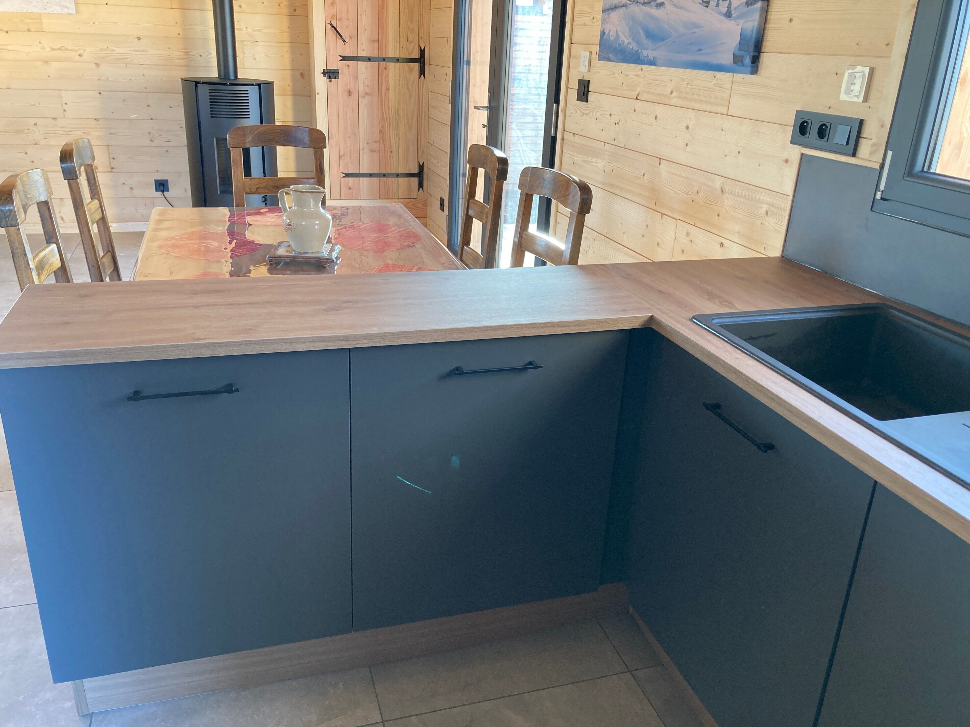 Une cuisine moderne avec une table en bois, des meubles noirs et un évier encastré.