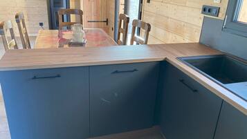 Une cuisine moderne avec une table en bois, des meubles noirs et un évier encastré.