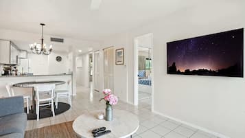 A modern living room with a round coffee table, a sofa, and a dining area with a kitchen in the background.