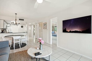 Un salon moderne avec une table basse ronde, un canapé et un coin repas, avec une cuisine en arrière-plan.