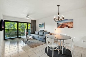 A modern living room with a sofa, dining table, chairs, and artwork on the wall.