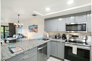 Una cocina moderna con encimeras de granito, electrodomésticos de acero inoxidable y armarios grises.