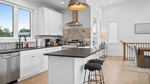 A modern kitchen with white cabinets, a large island, and a hanging light fixture.