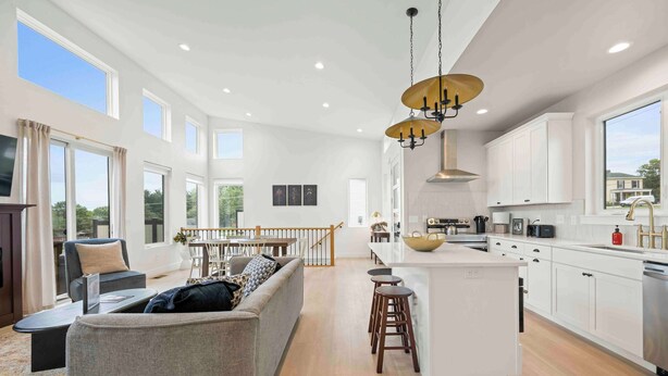 A spacious living area with a sofa, a dining table, and a kitchen with white cabinets and a large island.