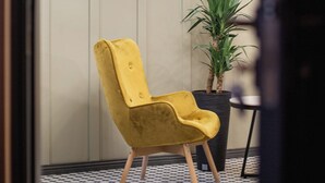 A yellow chair, a potted plant, and a neon sign reading "Nita" in a room with a checkered floor. - Boutique hotel tuta (Kutaisi)