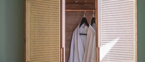 A wooden wardrobe with a semi-open door, featuring a woven back panel and a wooden interior.