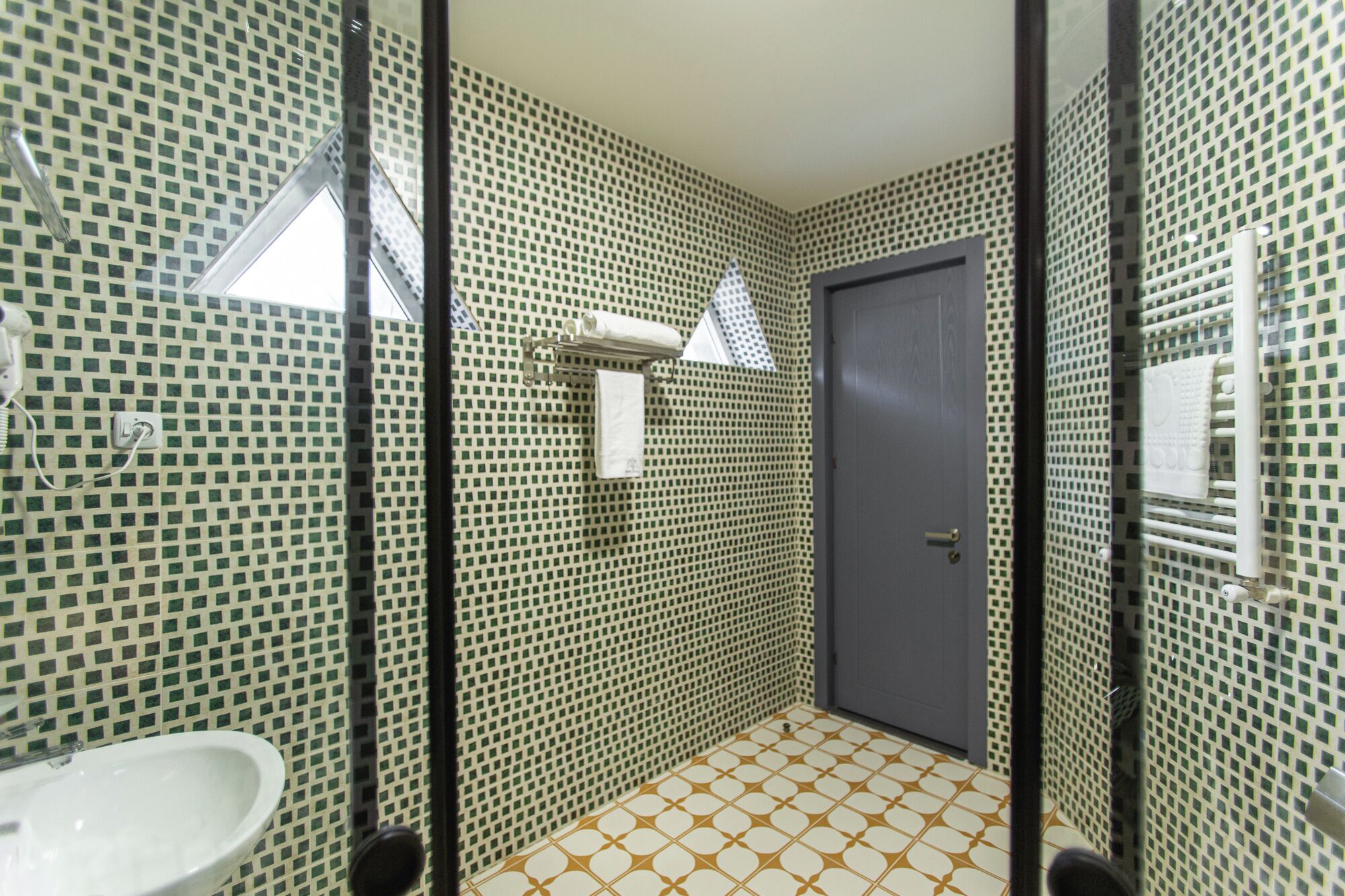 A bathroom with a sink, a mirror, a towel rack, and a door.