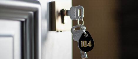 Una puerta con cerradura y una llave marcada con el número 104 insertada.
