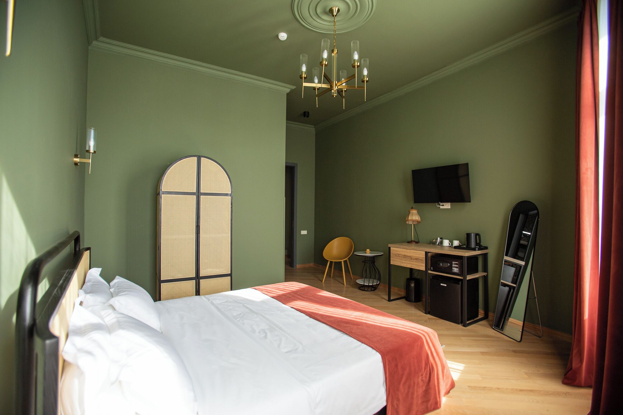 Un dormitorio con cama, escritorio, silla, televisor y espejo.