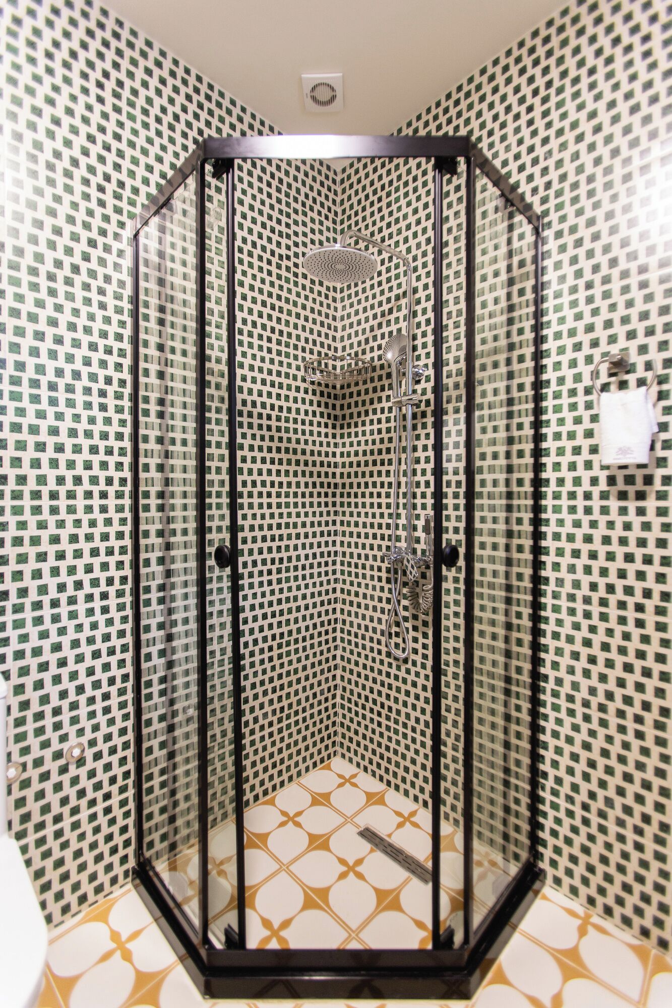 A corner shower with a black frame, tiled walls, and a patterned floor.