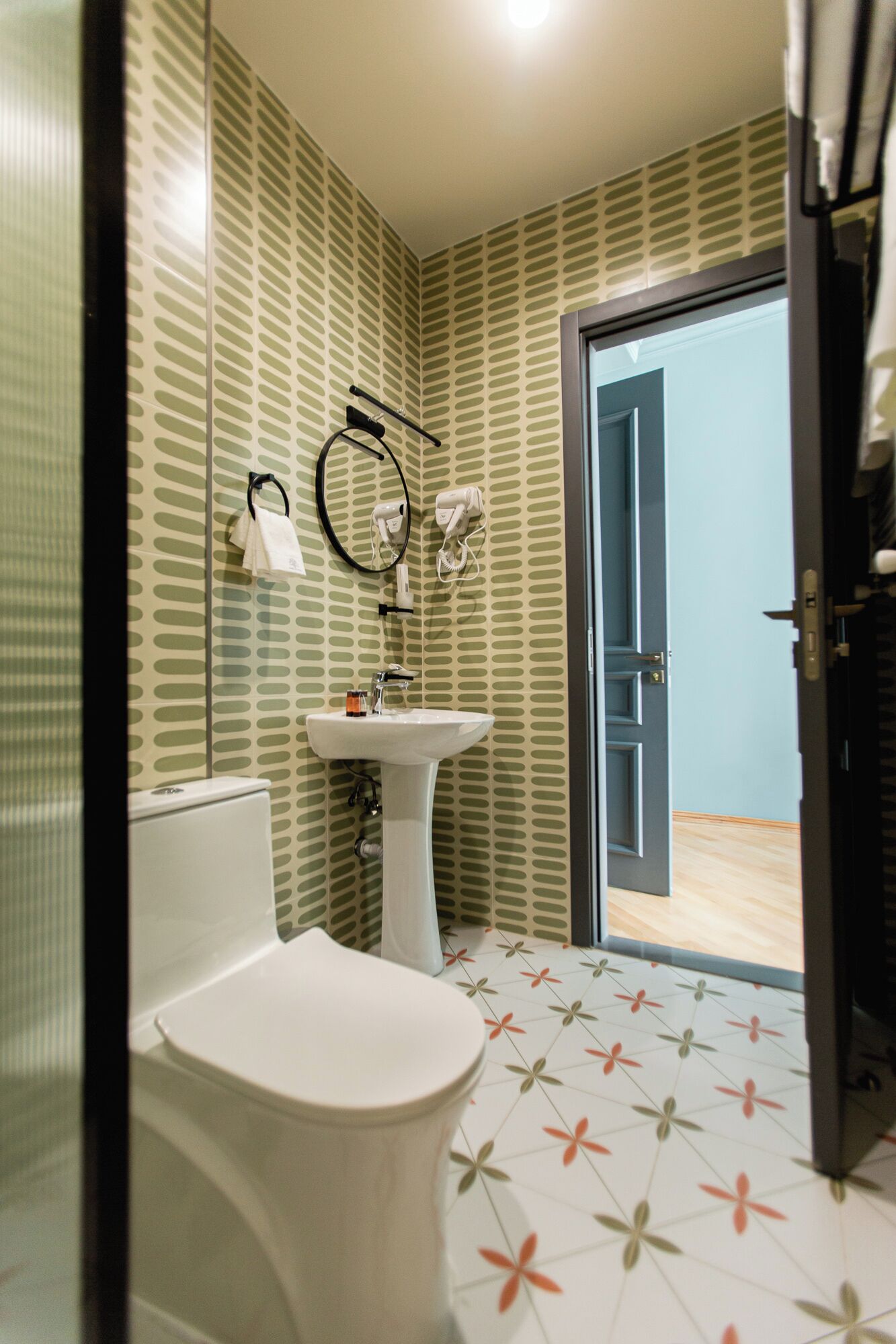 A bathroom with a toilet, sink, and hairdryer on the wall.