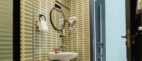 A bathroom with a toilet, sink, and hairdryer on the wall.