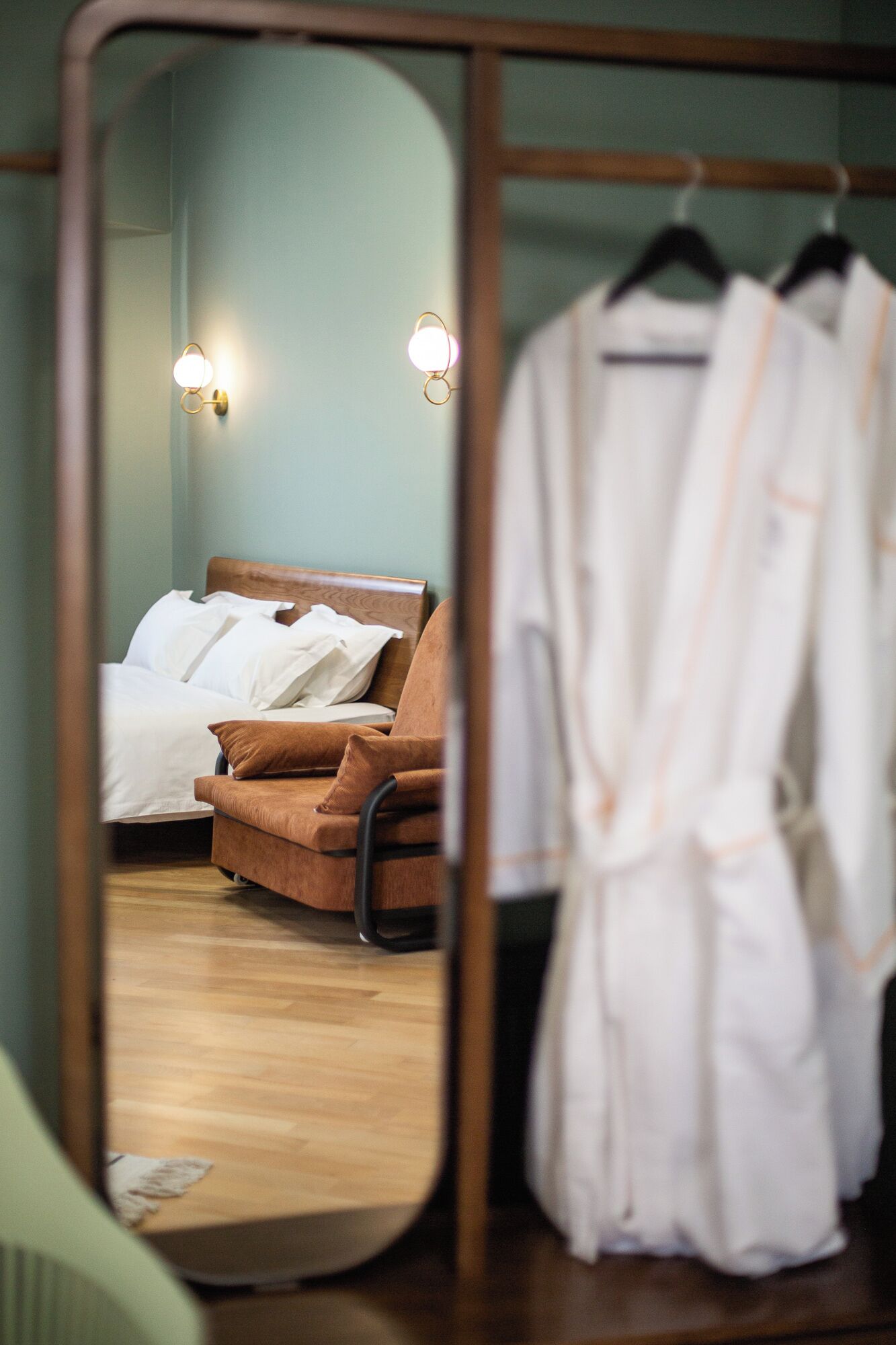 A bedroom with a bed, a chair, and a robe hanging on a rack.