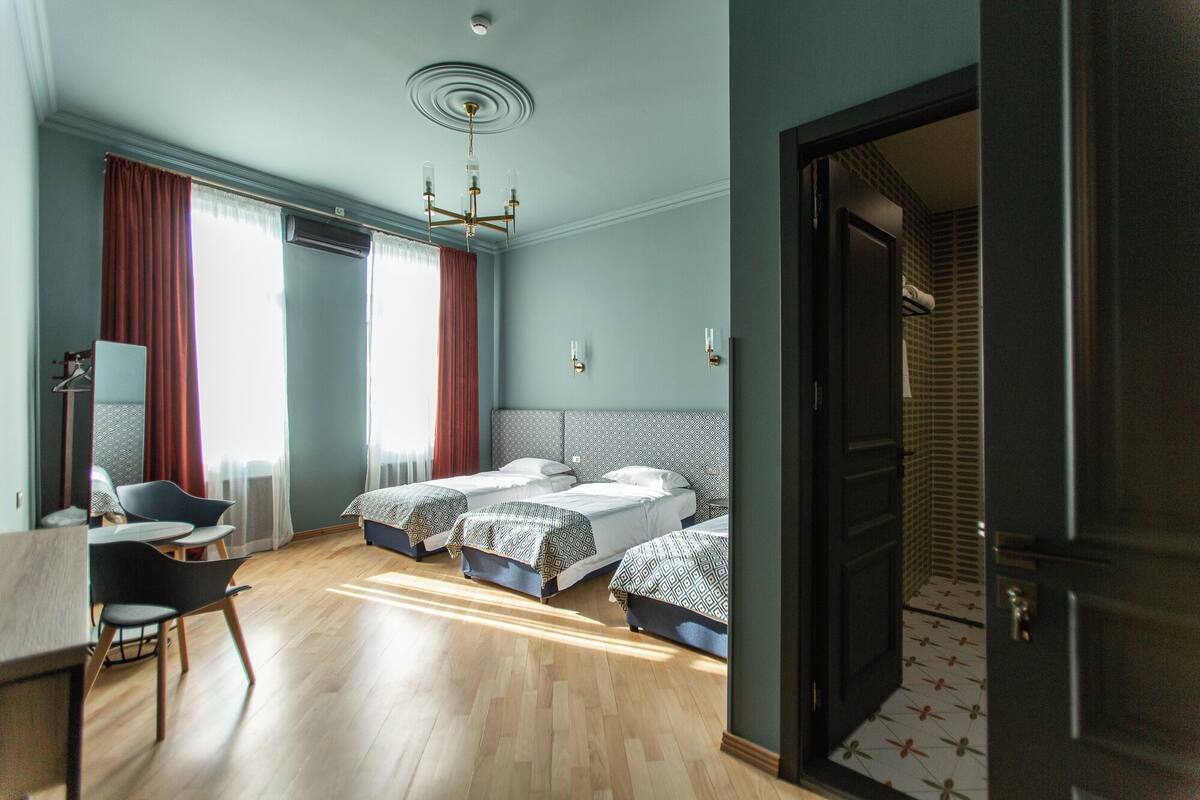 A hotel room with two beds, a desk, a chair, and a large mirror.