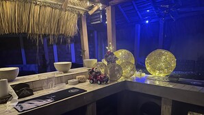 Un coin bar doté d’un plafond en chaume, de grands bols décoratifs et d’une petite voiture jouet.
