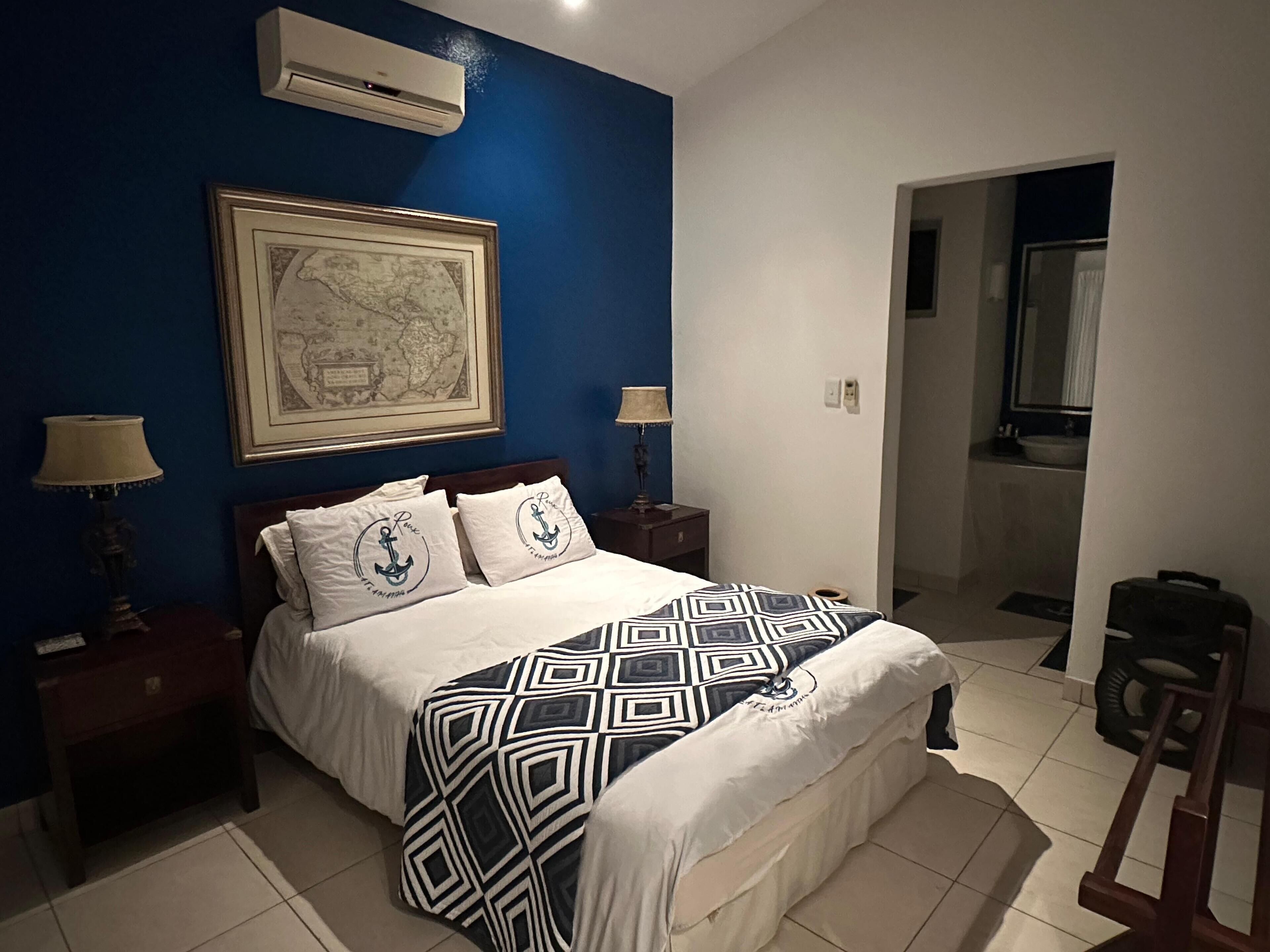 Una camera da letto con un letto, due comodini, una mappa appesa al muro e un condizionatore d'aria.