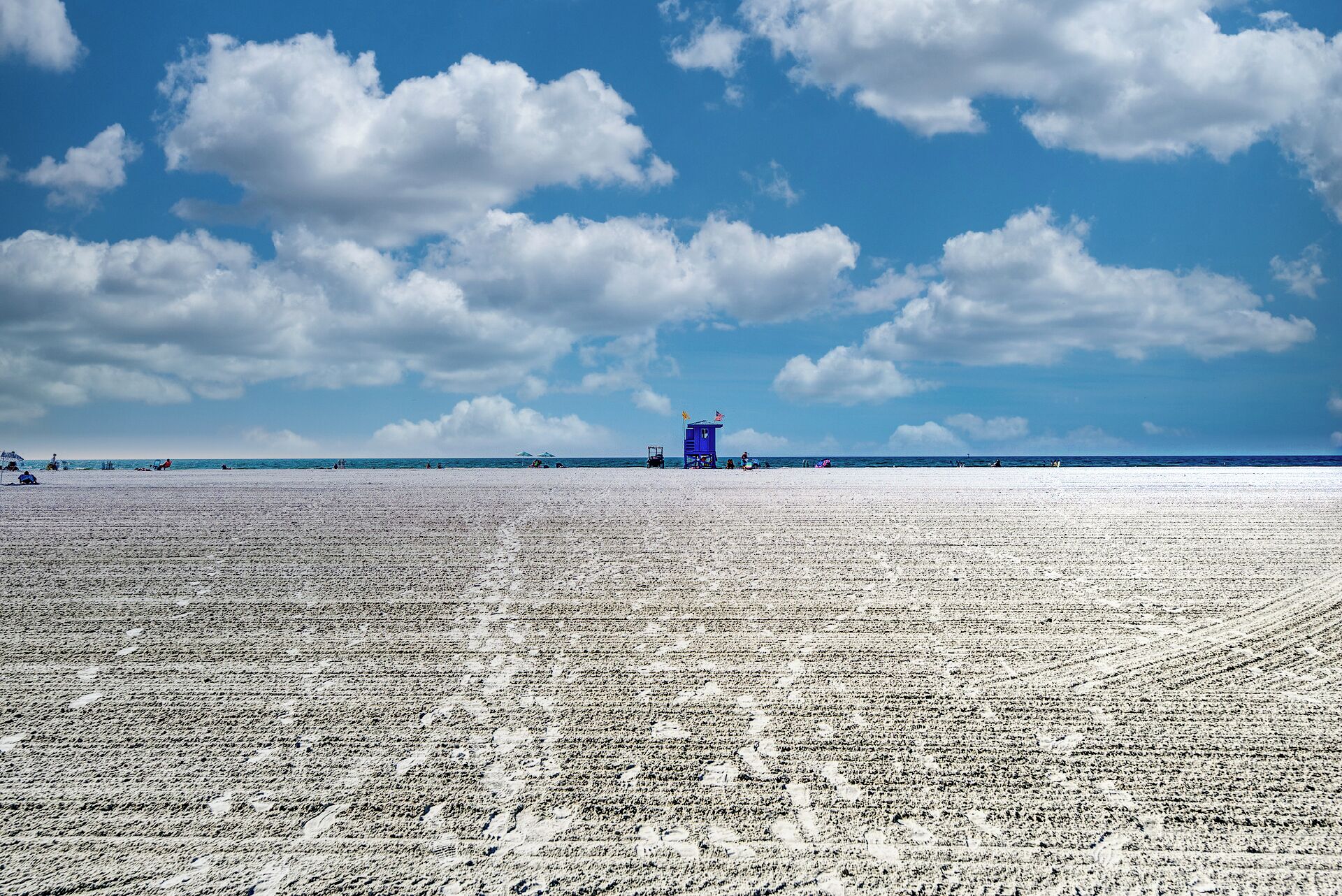 A wide beach with a lifeguard tower in the distance.