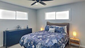 A bedroom with a bed, two bedside lamps, a ceiling fan, and a dresser. - Surfside Casa de Playa | Water Views (Surfside)
