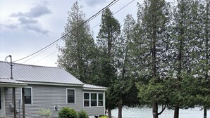 A single-story house with a metal roof, a front porch, and a lawn.