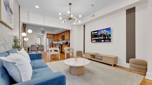 Una sala de estar moderna con un sofá azul, una mesa de centro redonda y un televisor montado en la pared.