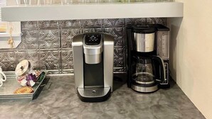 Een keuken met witte planken waarop borden, glazen en een koffiezetapparaat staan.