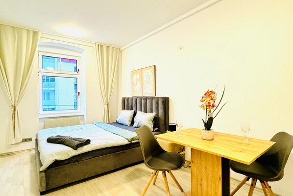 A bedroom with a bed, a window, a table, and chairs.