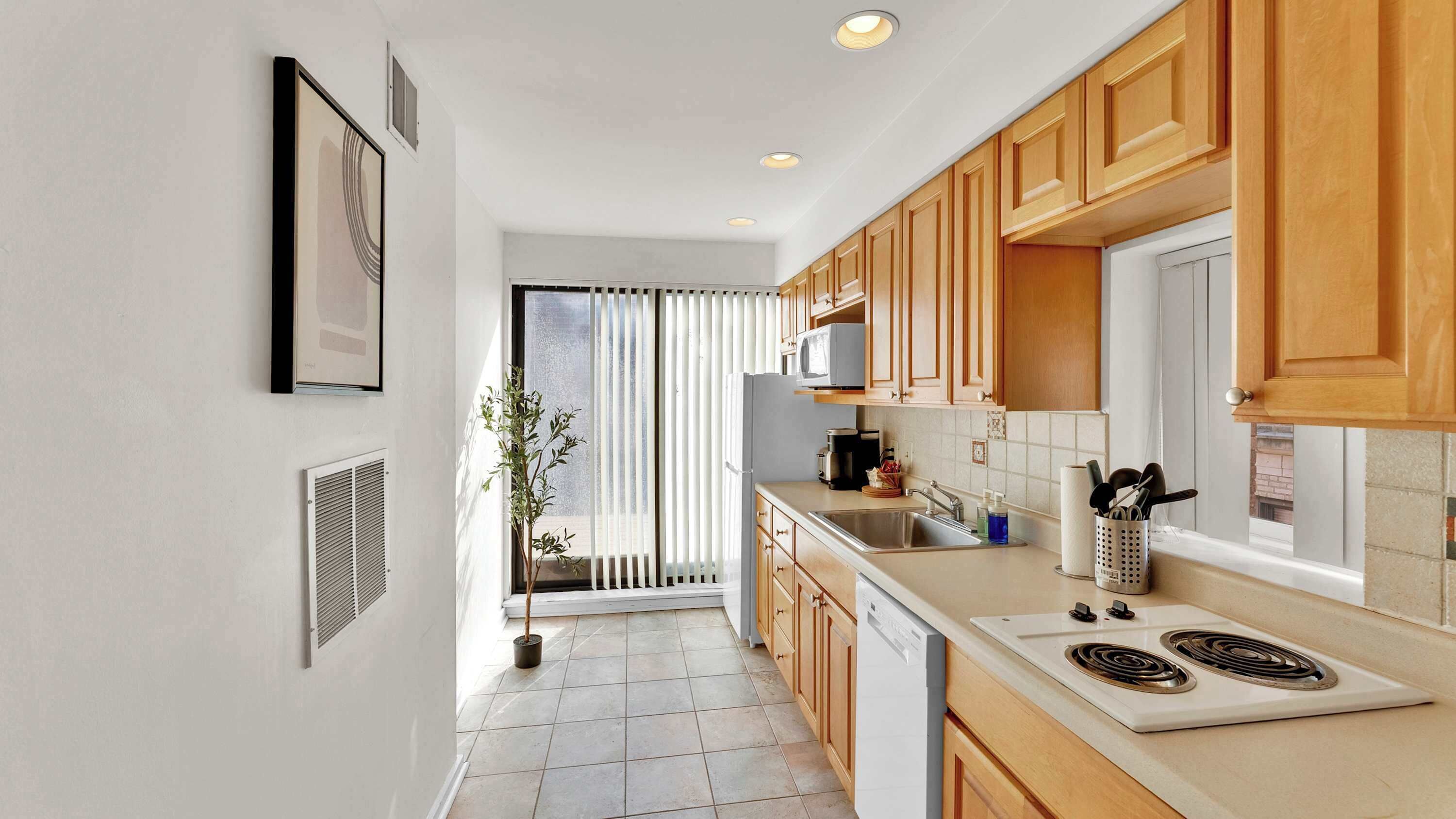 A modern kitchen with wooden cabinets, a white countertop, and a built-in microwave.