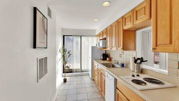 A modern kitchen with wooden cabinets, a white countertop, and a built-in microwave.