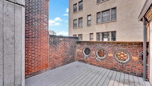 A rooftop patio with a brick wall and decorative circular windows. - Urban 1BR | Sleeps 4 | Steps to Rittenhouse Square (Philadelphia)