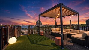 A rooftop terrace with a pergola, outdoor seating, and a view of the city skyline at sunset. - Grand Queen Village Retreat in Philly | Sleeps 16 (Philadelphia)