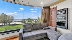 Ein modernes Wohnzimmer mit großem Fenster, einem grauen Ecksofa und einer eingebauten Unterhaltungseinheit.