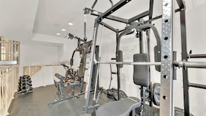 Ein Fitnessraum mit Squat-Gestell, Langhantelbank und verschiedenen Gewichtsplatten.
