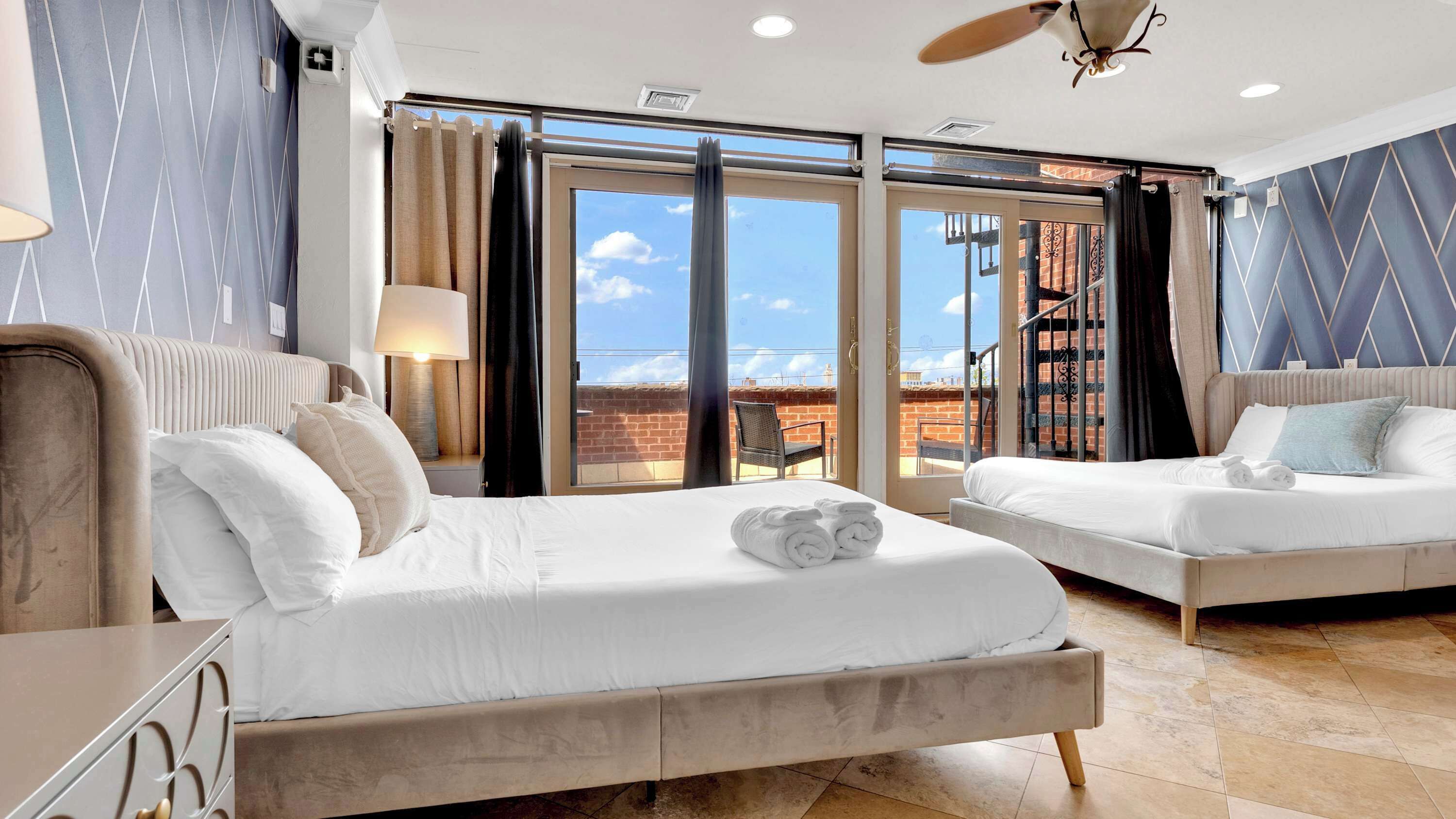 A hotel room with two beds, a balcony, and a view of the city.
