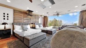 A modern hotel room with a large bed, a sofa, a chair, and a view of the city.