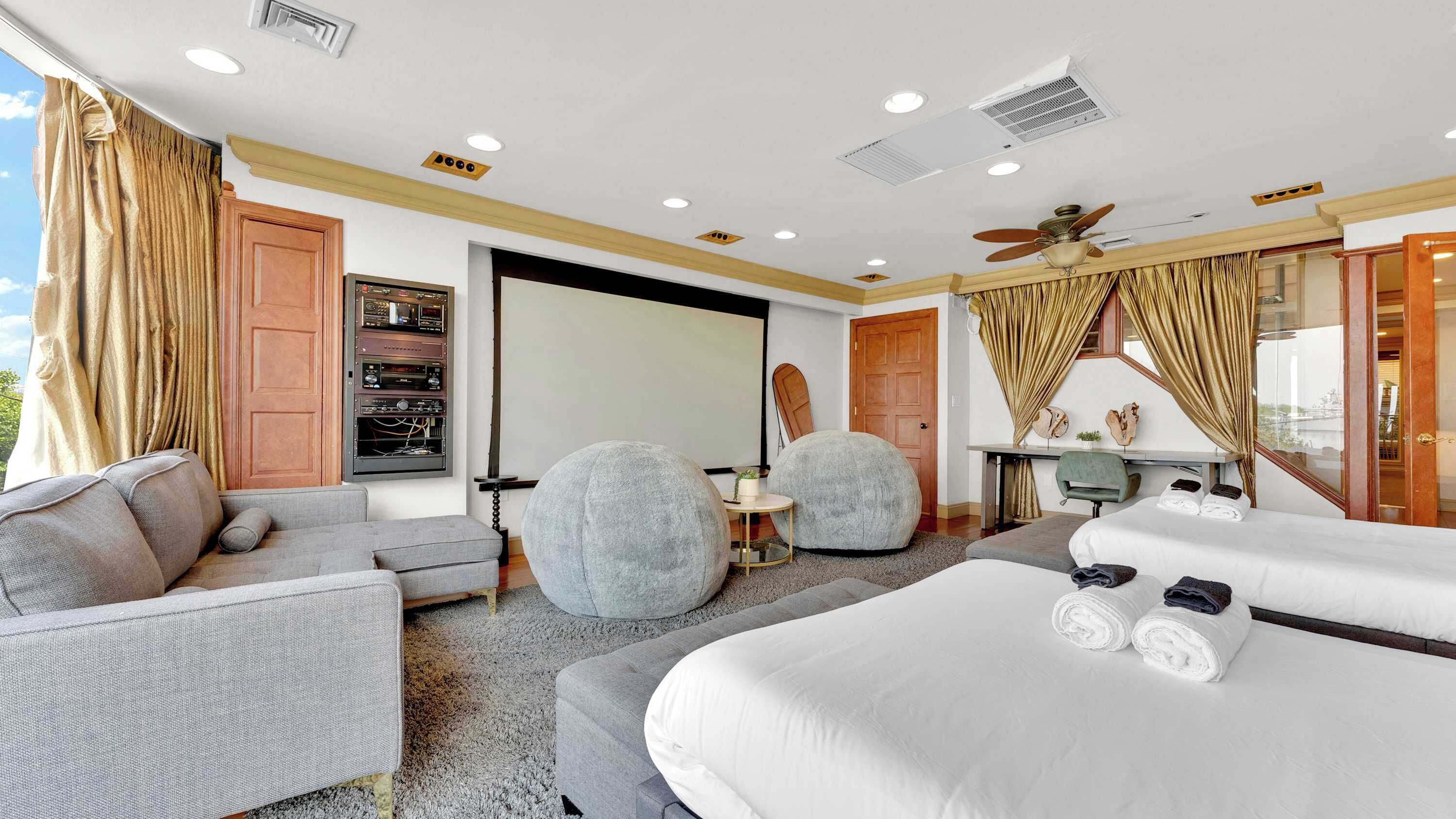 Une chambre d’hôtel avec un grand lit, un canapé, deux petits salons, un bureau et un ventilateur de plafond.