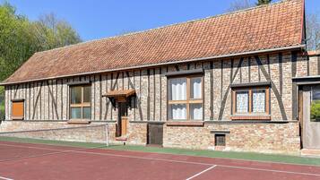 Un bâtiment traditionnel à colombages avec un court de tennis situé devant.