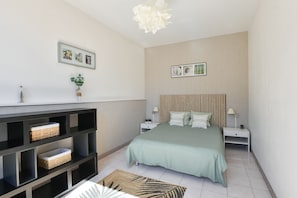 A modern bedroom with a bed, nightstands, a console table, and wall art.