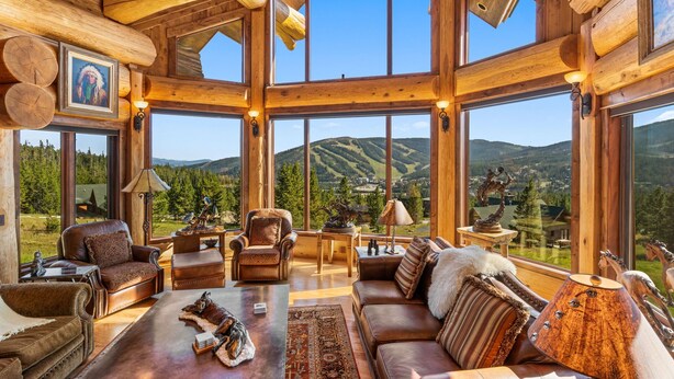 Un intérieur spacieux de chalet en bois, doté de grandes fenêtres offrant une vue sur les montagnes.